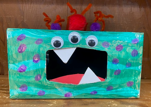 Green tissue box monster with purple polka dots and orange hair