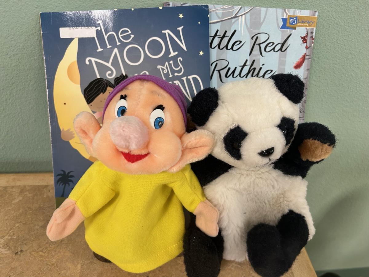 Dopey and Panda hand puppets leaning against two books