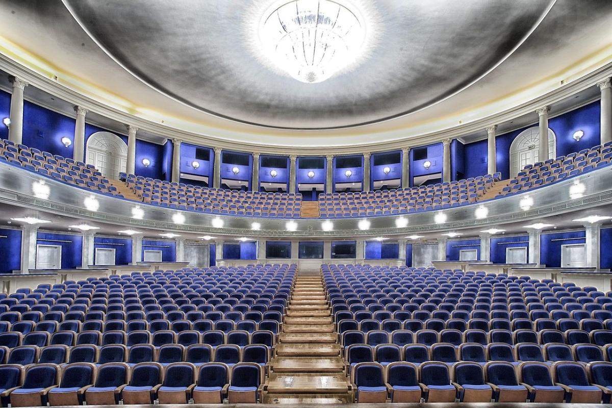 Inside a theater with rows of blue chairs