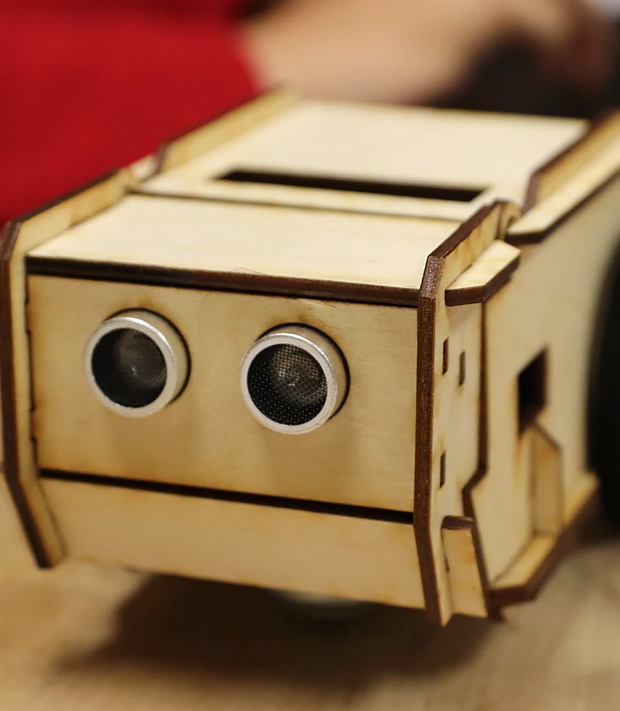 Small robot made of laser-cut wood pieces with dark electronic eyes