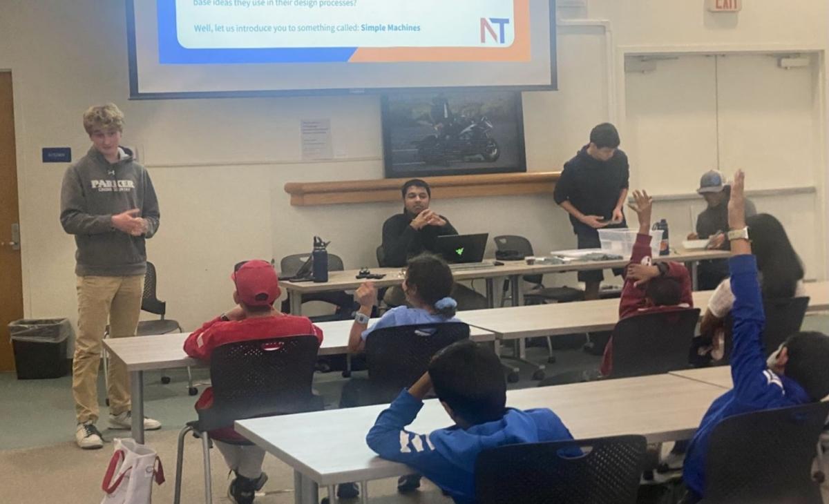 Students sitting at tables listening to an older student instructor