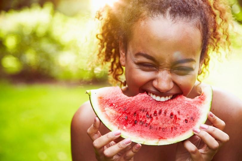 Image of an individual biting into a slice of watermelon.
