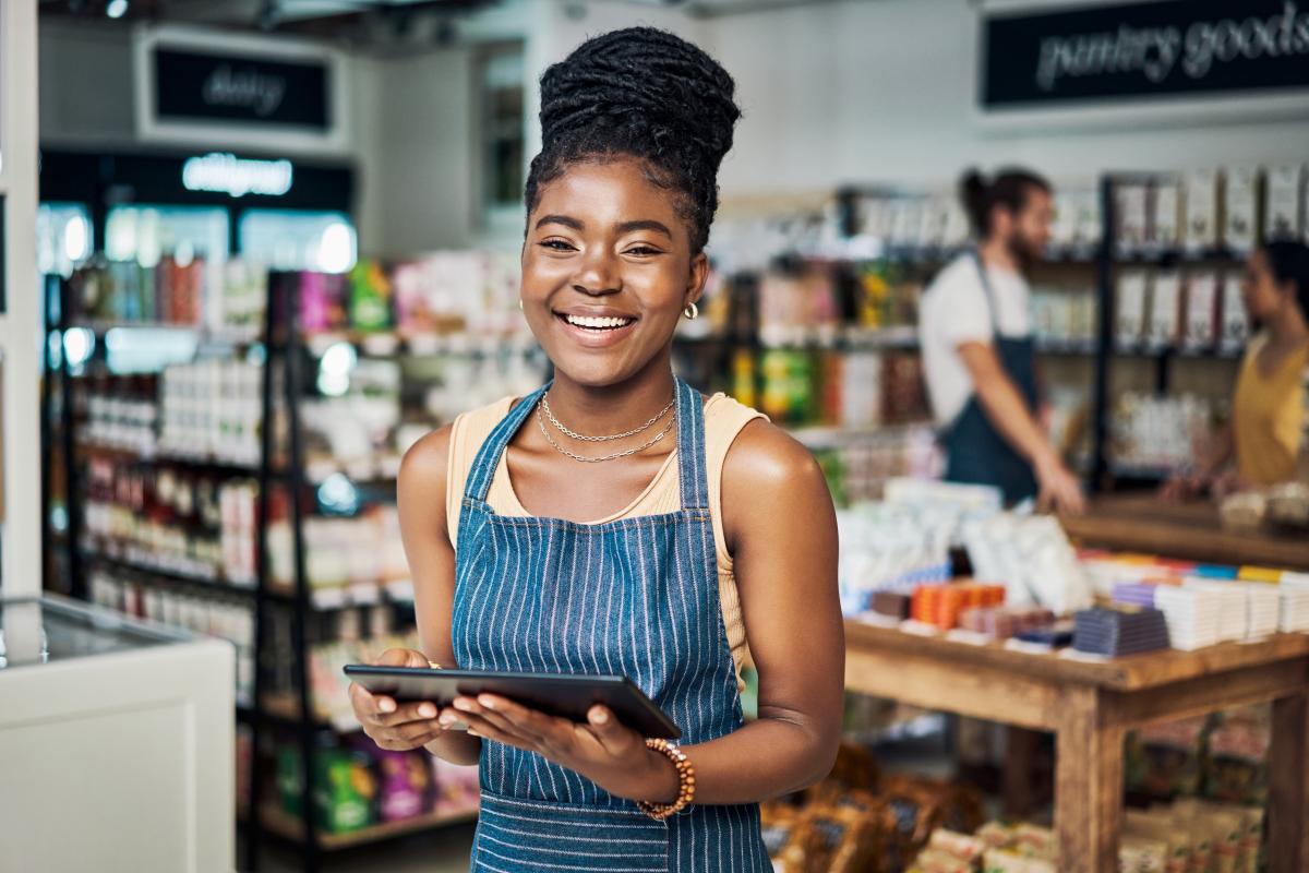 young woman wearing apron and holding tablet in a shop