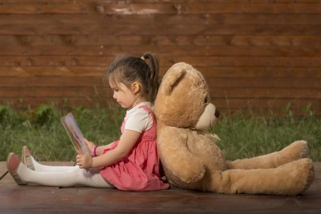 Girl reading with teddy bear